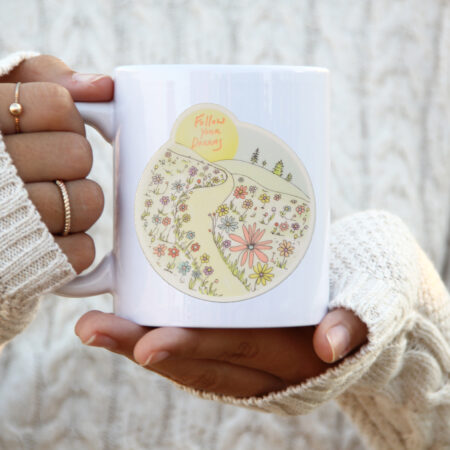 follow your dreams on mug with woman and white sweater and rings
